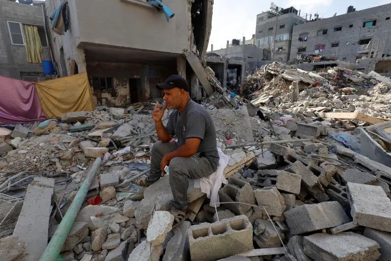A Palestinian man from the Kullab family, whose home in Khan Younis in southern Gaza was damaged in an Israeli strike, sits on the rubble