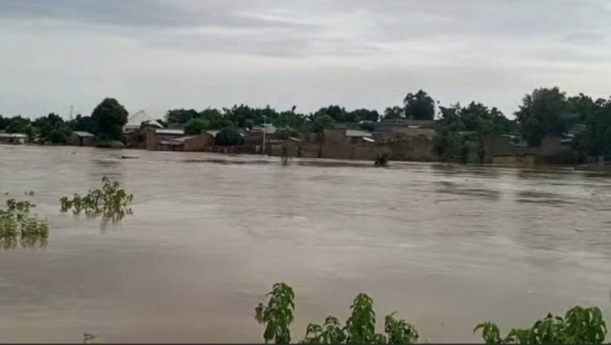 Flooded street in Nigeria with residents navigating water during heavy rainfall.